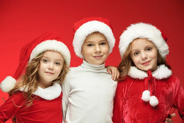 Счастливый мальчик и девочки в шляпах Санта-Клауса с подарочными коробками в студии — стоковое фото