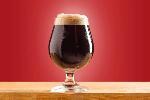 Glas koud schuimig donker bier op een oud houten tafel — Stockfoto