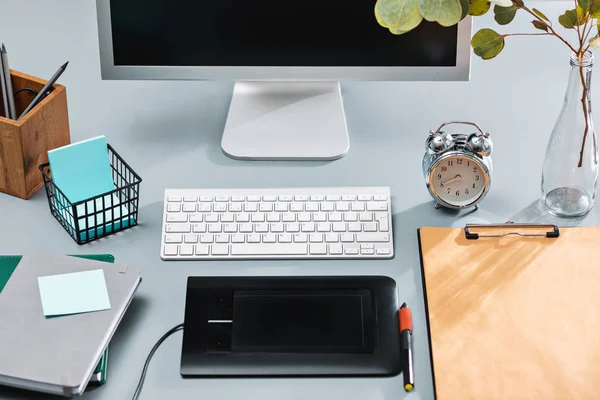 Серый стол с ноутбуком, блокнот с чистым листом, цветочный горшок, стилус и планшет для ретуши — стоковое фото