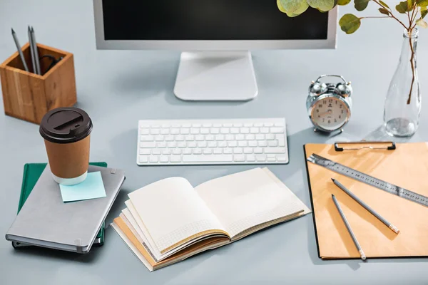 A mesa cinza com laptop, bloco de notas com folha em branco, vaso de flor, estilete e tablet para retoque — Fotografia de Stock