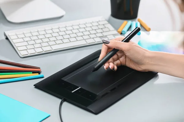 A mesa cinza com laptop, bloco de notas com folha em branco, vaso de flor, estilete e tablet para retoque — Fotografia de Stock