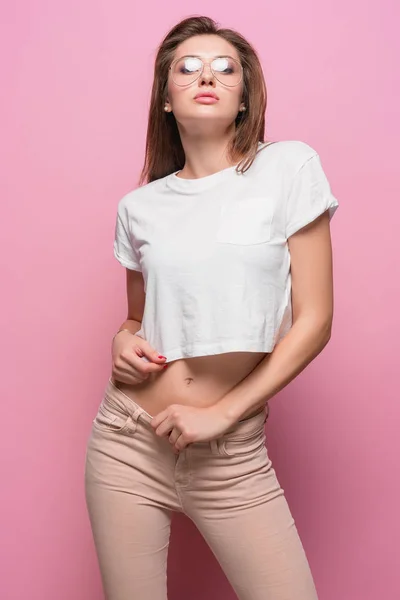 Mujer sensual de moda sexy bastante joven posando sobre fondo rosa vestida con jeans de estilo hipster — Foto de Stock