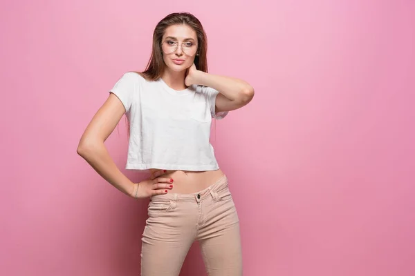 Mujer sensual de moda sexy bastante joven posando sobre fondo rosa vestida con jeans de estilo hipster —  Fotos de Stock