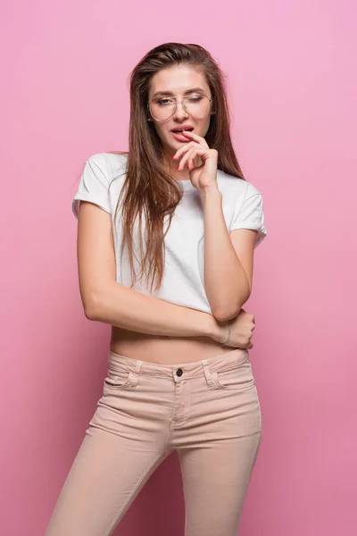 Pretty young sexy fashion sensual woman posing on pink background dressed in hipster style jeans — Stock Photo, Image