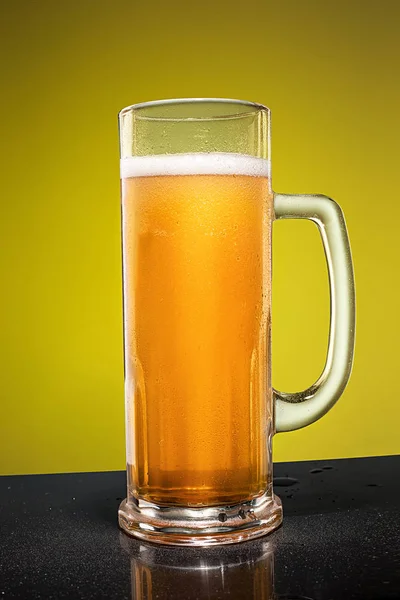 Glass of cold frothy lager beer on an old wooden table — Stock Photo, Image