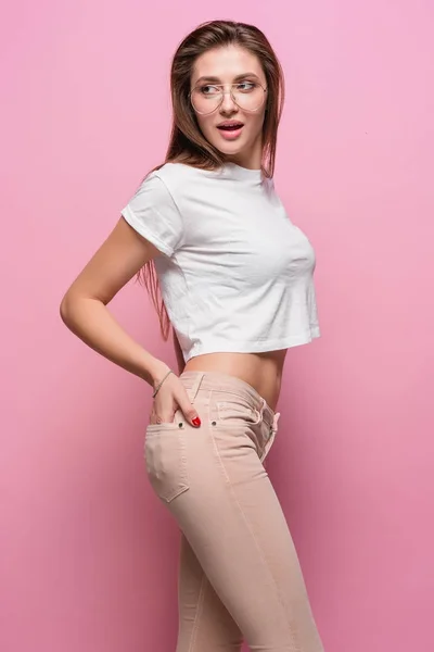 Довольно молодая сексуальная чувственная женщина моды позирует на розовом фоне в джинсах в хипстерском стиле — стоковое фото
