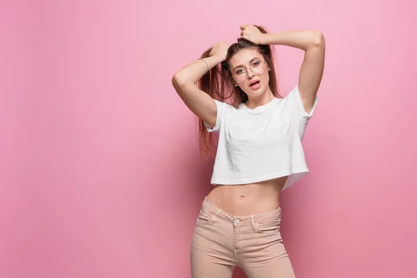 Pretty young sexy fashion sensual woman posing on pink background dressed in hipster style jeans — Stock Photo, Image