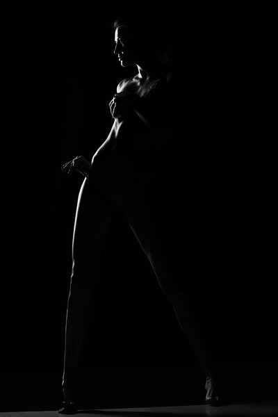 Black and white silhouette of young, sporty and sexy woman in lingerie on black studio background