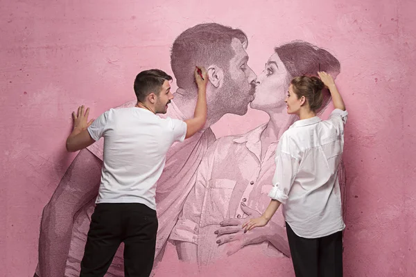 Il collage sulla coppia che scrive qualcosa su un muro rosa — Foto Stock