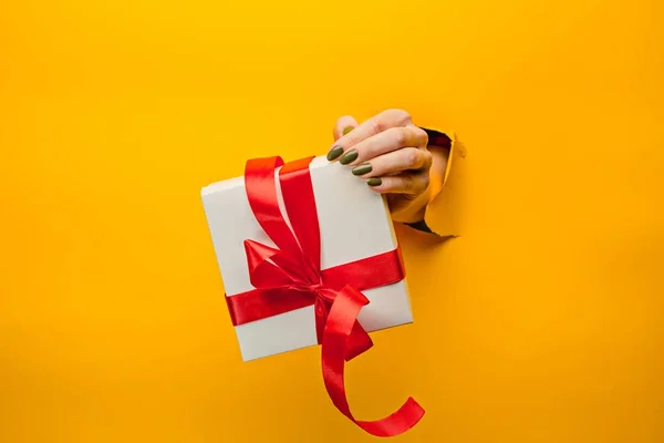 Bir hediye izole bir yırtık kağıt üzerinden tutan el Close-Up — Stok fotoğraf
