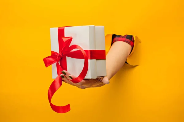 Bir hediye izole bir yırtık kağıt üzerinden tutan el Close-Up — Stok fotoğraf