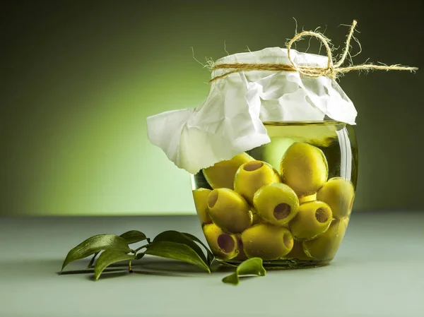 Aceite de oliva y rama de olivo sobre la mesa de madera — Foto de Stock