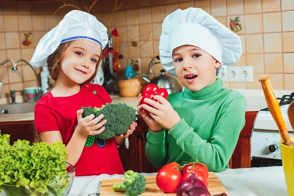 Happy family funny kids are preparing the a fresh vegetable salad in the kitchen — Stock Photo, Image