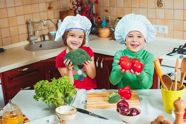 Happy family funny kids are preparing the a fresh vegetable salad in the kitchen — Stock Photo, Image