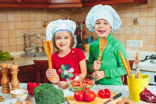 Счастливая семья забавные дети готовят свежий овощной салат на кухне — стоковое фото