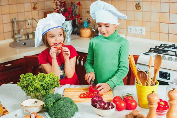面白い子供たちを準備している幸せな家族、キッチンで新鮮な野菜のサラダ ストック写真