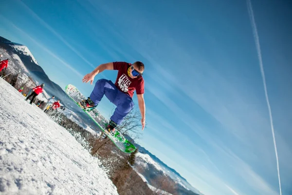 Boekovel, Oekraïne - 22 December 2016: Man boarder springen op zijn snowboard tegen de achtergrond van bergen, heuvels en bossen in de verte. Boekovel, Karpaten — Stockfoto