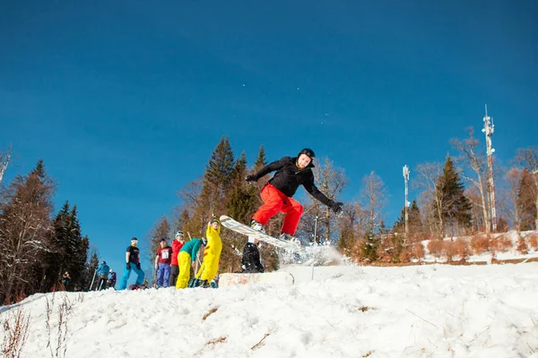 Boekovel, Oekraïne - 22 December 2016: Man boarder springen op zijn snowboard tegen de achtergrond van bergen, heuvels en bossen in de verte. Boekovel, Karpaten — Stockfoto