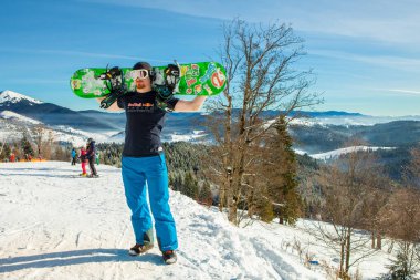 Bukovel, Ukrayna - 22 Aralık 2016: dağlar, tepeler ve mesafe ormanlarda fon karşı onun snowboard tutan adam. Bukovel, Karpat Dağları