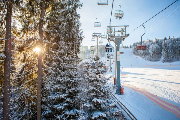 Skifahrer mit dem Skilift fahren in das Skigebiet mit wunderschönem Hintergrund von schneebedeckten Pisten, Wäldern, Hügeln in Bukovel, Ukraine — Stockfoto