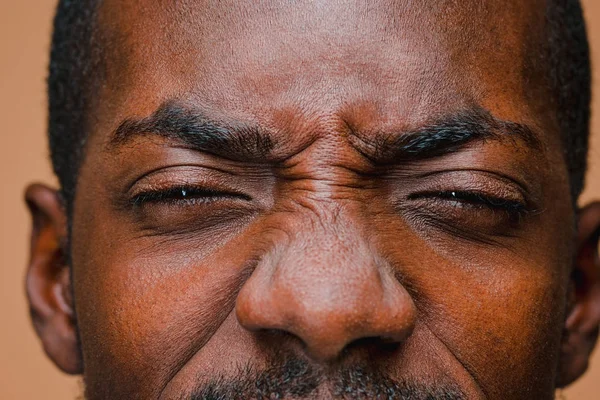 De squint Afro Amerikaanse stijlvolle man op bruin studio muur — Stockfoto