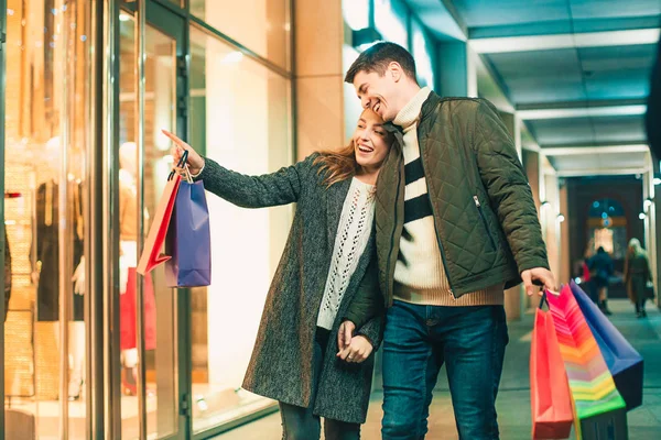 La feliz pareja con bolsas de compras disfrutando de la noche en el fondo de la ciudad — Foto de Stock