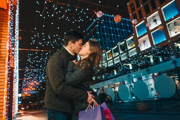 Het gelukkige paar met boodschappentassen, genieten van de nacht op de stad achtergrond — Stockfoto