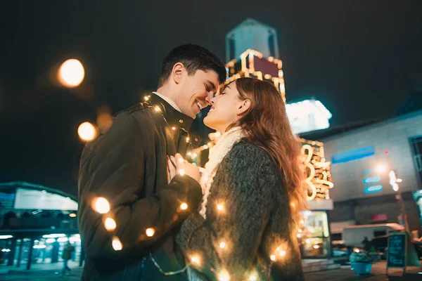 Νεαρό ζευγάρι φιλί και αγκαλιάζει εξωτερική νύχτα δρόμου στο χρόνο Χριστουγέννων — Φωτογραφία Αρχείου