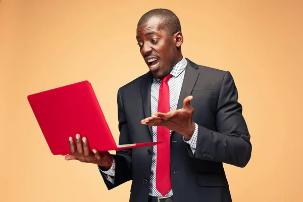 Bonito afro-americano sentado e usando um laptop — Fotografia de Stock