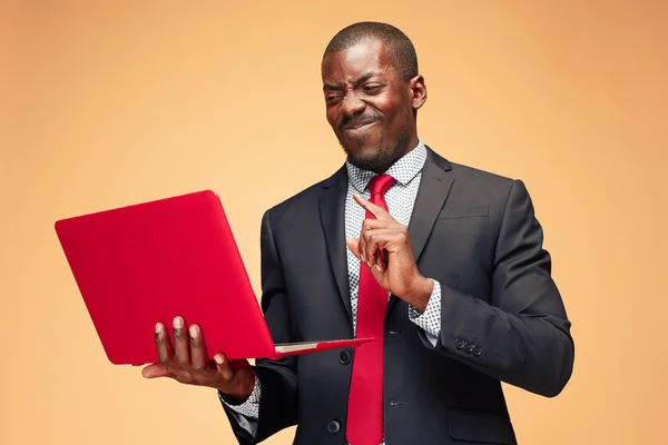Schöner afroamerikanischer Mann sitzt und einen Laptop benutzt — Stockfoto