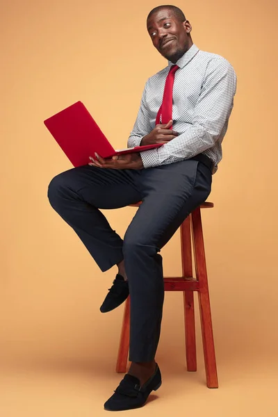 Hombre afroamericano guapo sentado y usando una computadora portátil —  Fotos de Stock