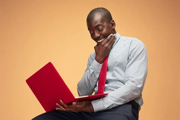 Schöner afroamerikanischer Mann sitzt und einen Laptop benutzt — Stockfoto