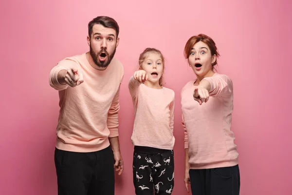 Surpreendido jovem família olhando para a câmera em rosa — Fotografia de Stock