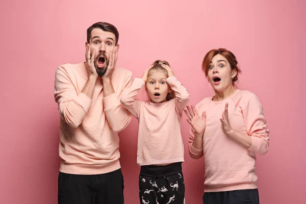 Surpreendido jovem família olhando para a câmera em rosa — Fotografia de Stock