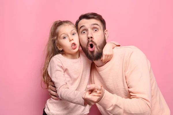 Surpreendido jovem família olhando para a câmera em rosa — Fotografia de Stock