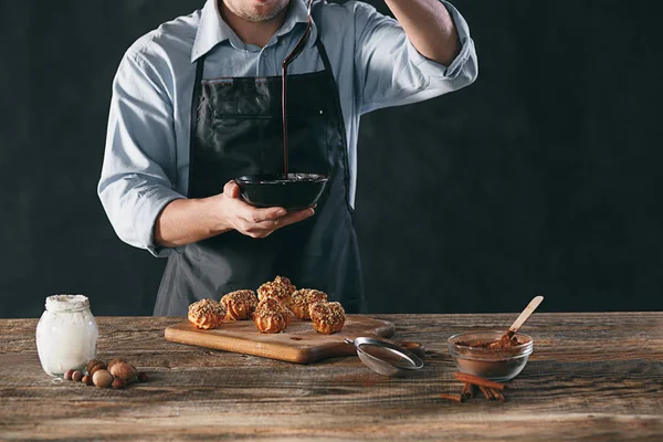 stock image Decorating delicious homemade eclairs with chocolate and peanuts