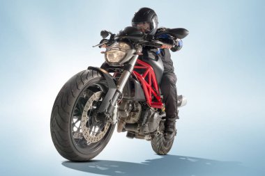 Motorcu siyah ceket ve sportif bisikletini mavi zemin üzerine oturan kask