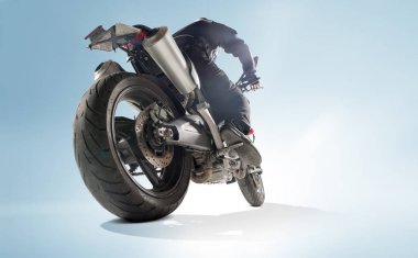 Motorcu siyah ceket ve sportif bisikletini mavi zemin üzerine oturan kask