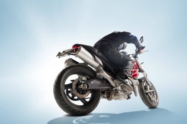 Motorcu siyah ceket ve sportif bisikletini mavi zemin üzerine oturan kask