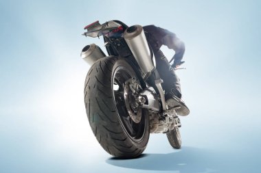 Motorcu siyah ceket ve sportif bisikletini mavi zemin üzerine oturan kask