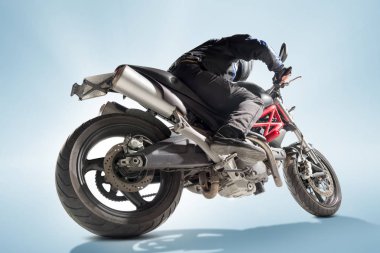 Motorcu siyah ceket ve sportif bisikletini mavi zemin üzerine oturan kask