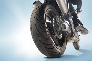 Motorcu siyah ceket ve sportif bisikletini mavi zemin üzerine oturan kask