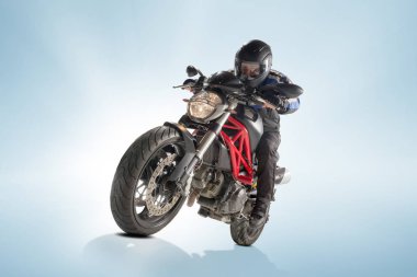 Motorcu siyah ceket ve sportif bisikletini mavi zemin üzerine oturan kask