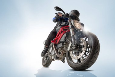 Motorcu siyah ceket ve sportif bisikletini mavi zemin üzerine oturan kask