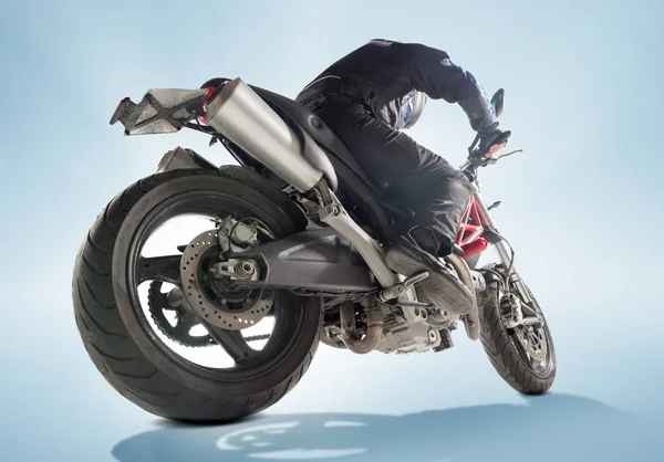 Motorcu siyah ceket ve sportif bisikletini mavi zemin üzerine oturan kask