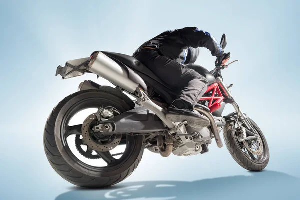 Motorcu siyah ceket ve sportif bisikletini mavi zemin üzerine oturan kask