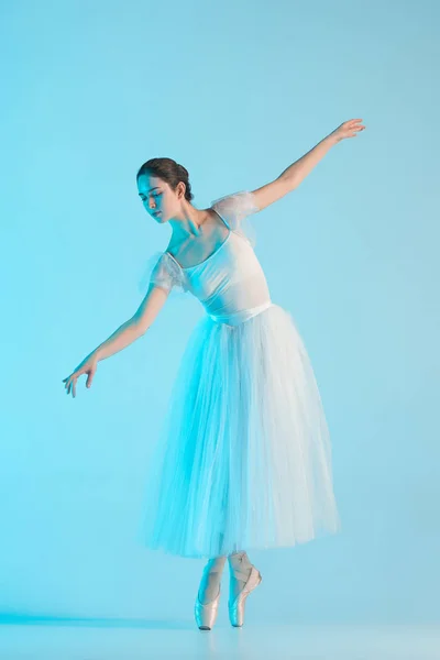 Jovem e incrivelmente bela bailarina está dançando em um estúdio azul — Fotografia de Stock