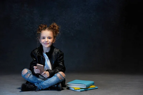 Niña sentada con smartphone en estudio — Foto de Stock