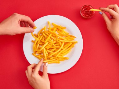 Genç kadın bir restoranda ketçap ile kızarmış patates patates yeme