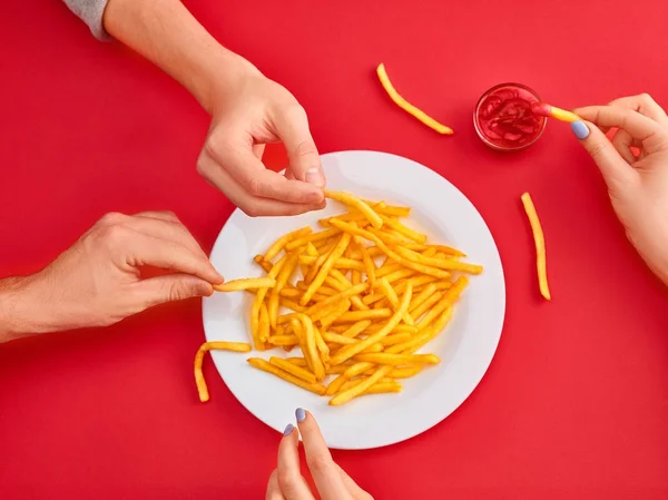 Mujer joven comiendo papas fritas con ketchup en un restaurante — Foto de Stock